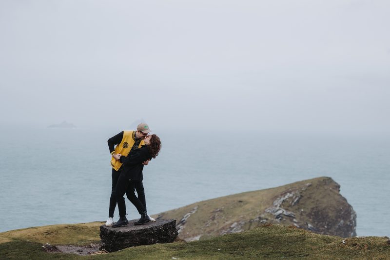 Couple kissing on a coastal cliff overlooking the sea