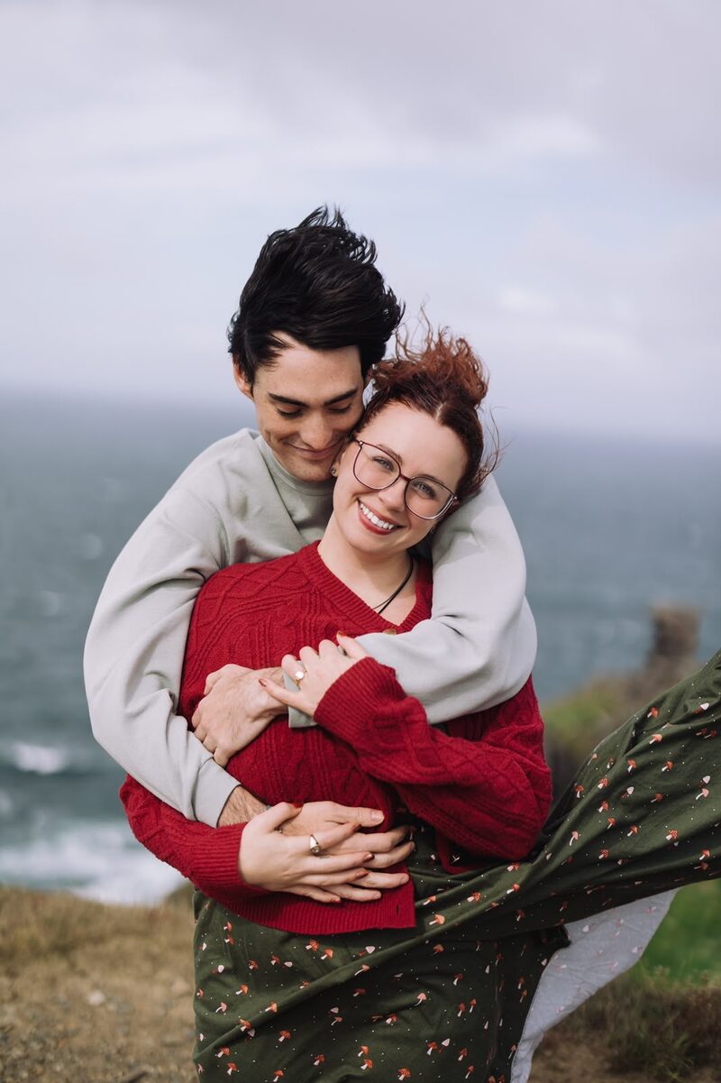 Engaged couple embracing on the cliffs with the Atlantic behind them