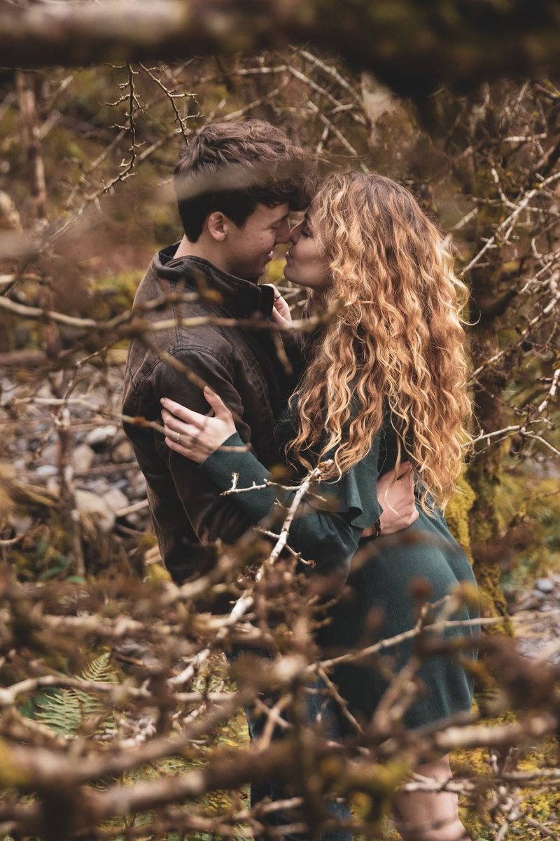 Couple sharing a kiss among bare branches in the woods