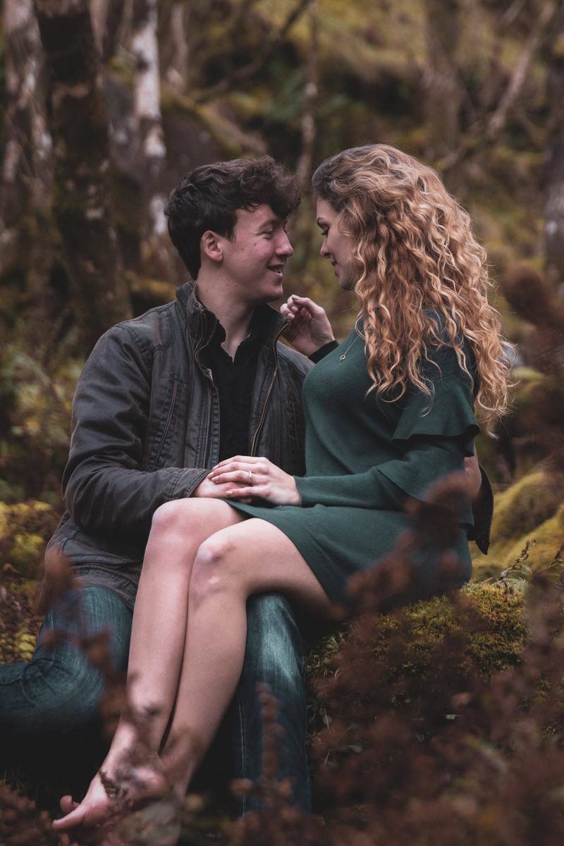 Couple sitting together on a mossy log in the forest