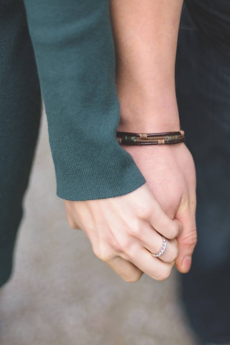 Close-up of the couple holding hands, showing an engagement ring and bracelet