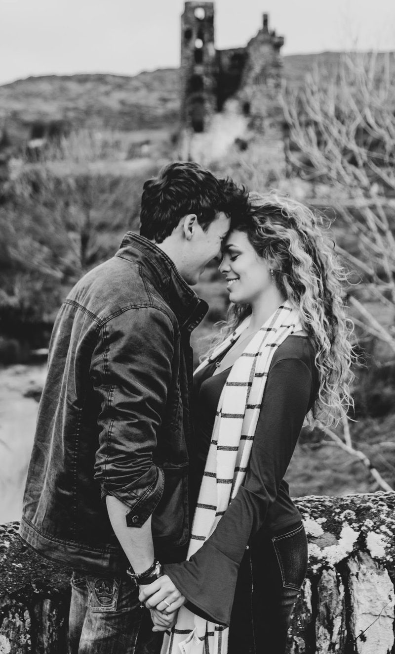 Black and white photo of a couple with foreheads touching in front of ancient ruins