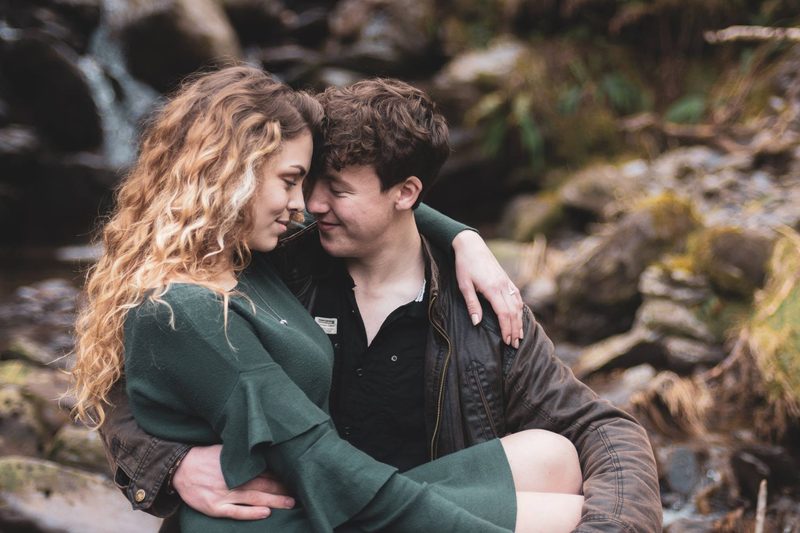 Couple embracing beside a mossy stream in the woods