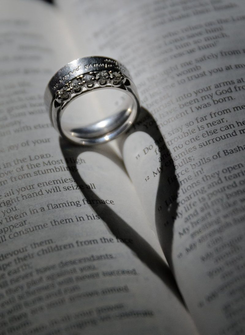Diamond ring casting a heart-shaped shadow across an open Bible