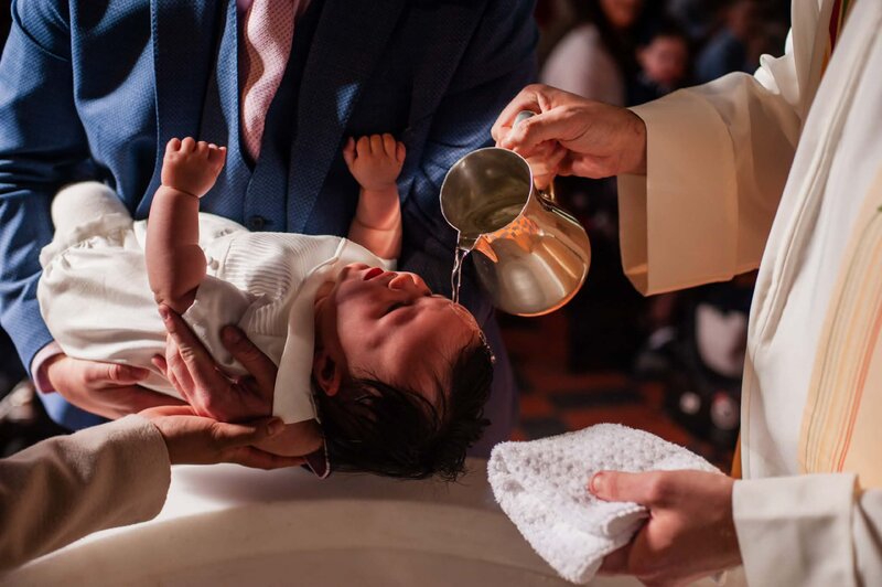Baby being christened with water poured over the head during a baptism ceremony