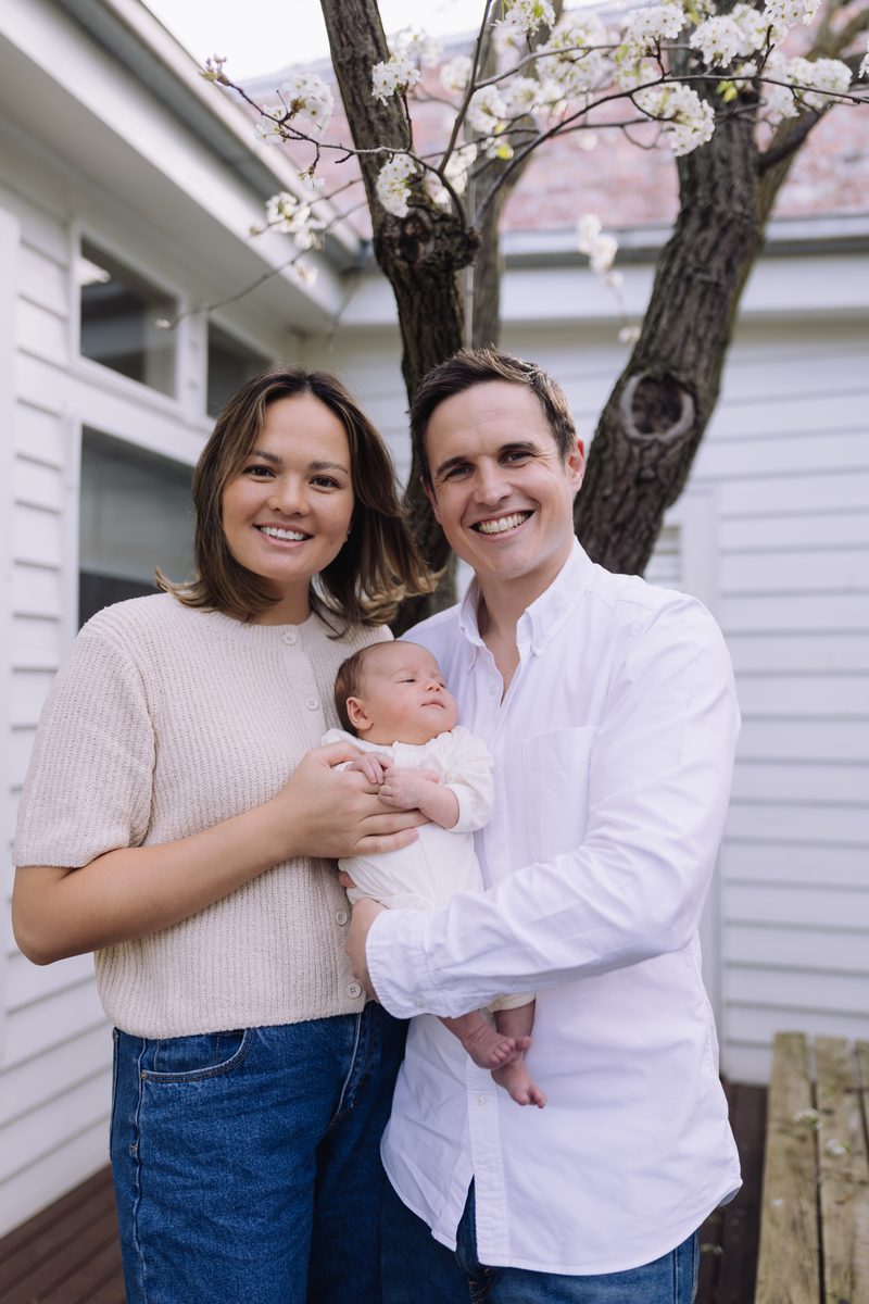 Parents smiling with their newborn baby in a garden