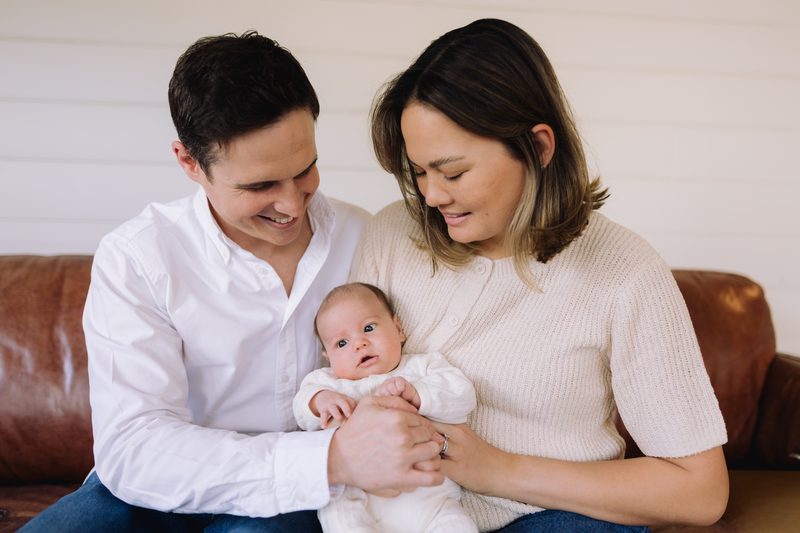 Parents holding their newborn baby on a couch
