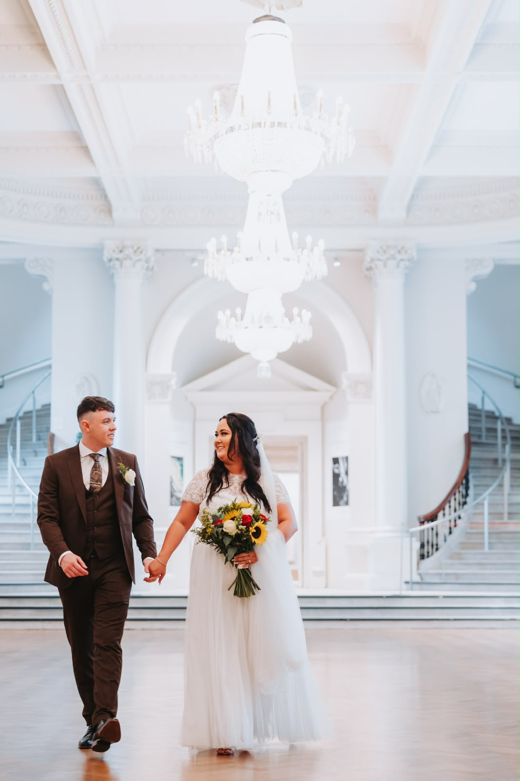 Bride and groom walking under a grand chandelier